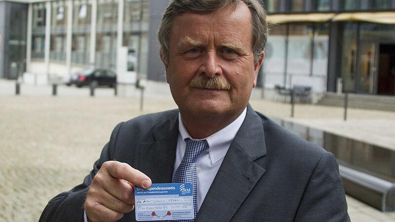 The head of German Medical Association Montgomery shows his organ donation card to reporters before crisis session in Berlin